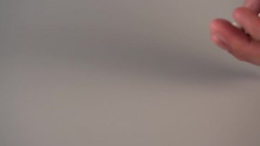 Bir adamın eli gri bir masanın üzerine koyu ve beyaz tıbbi kapsüller döker.