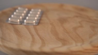 Tıbbi kapsül paketleri gri bir arka plan üzerinde ahşap doku yüzeyine yukarıdan düşmek. Yavaş çekim. Sağlık Sigortası Sorunları Kavramı