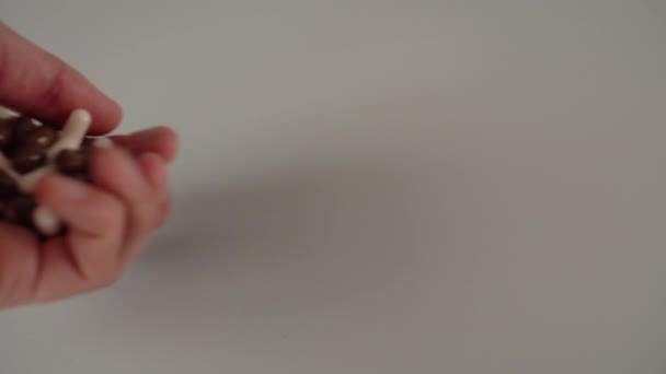 Main renverse des capsules médicales brunes et blanches en poignée sur fond gris 