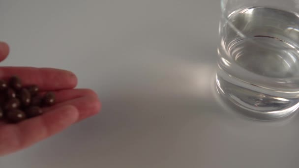 Een Hand Morst Een Handvol Donker Bruine Medische Capsules Een — Stockvideo