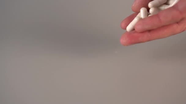 Les capsules médicales blanches tombent d'en haut sur une table grise. Le concept de l'utilisation de remèdes homéopathiques. Mouvement lent 