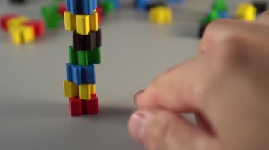 Renkli figürlerin tasarımı. El piramidin tabanından birini kaldırır. Düşer, parçaları farklı yönlere düşer. Kötü iş yönetimi kavramı