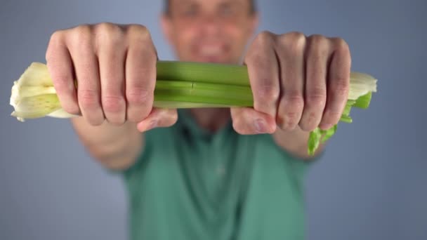 Man Green Shirt Breaks Bunch Celery Blue Background Selective Focus — Stock Video