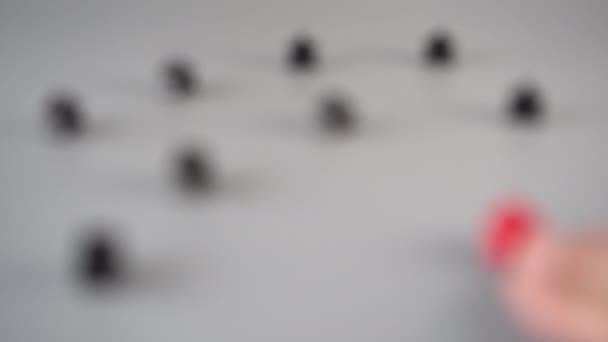 Una Mano Coloca Una Figura Roja Rodeada Figuras Negras Sobre — Vídeos de Stock