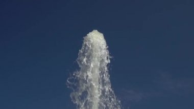 Yüksek bir çeşme jetmavi bir yaz gökyüzüne karşı yükselir. Yavaş çekim