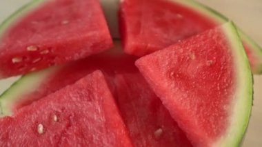 Dilimlenmiş karpuz ahşap bir yüzeyüzerinde döner. Taze yazın tadı. Susuz tedavi