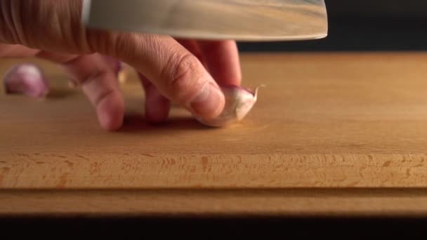 厨师在木质表面用刀切大蒜 在黑色背景上 慢动作 烹饪蔬菜饮食餐 — 图库视频影像