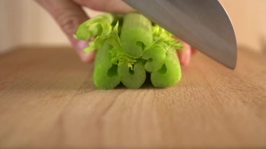 Bir aşçı, tahta bir yüzeyde bıçakla kereviz keser. Vücudu temizlemek için sebze salataları ve diğer diyet yemekleri hazırlanması