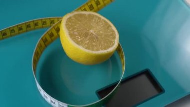 Çok renkli bir santimetre bir akuamarin zemin ölçeğinde bir limon etrafında halkalar iner. Formda kalmak için araçlar, diyet