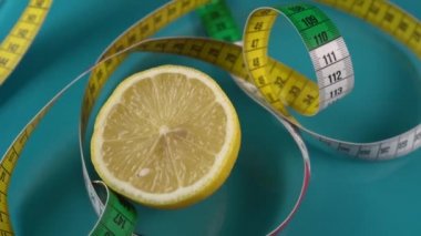 Akuamarin taban pullarında çok renkli bir santimetre ve yarım adet taze limon bulunmaktadır. Sağlıklı gıdalar ve kilo yönetimi araçları. Yukarıdan görüntüle