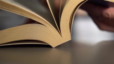 Adam eski bir kitaptan geçerek, gri bir yüzeydeki sayfaları çevirir. Yavaş çekim. Bilgi Kavramı