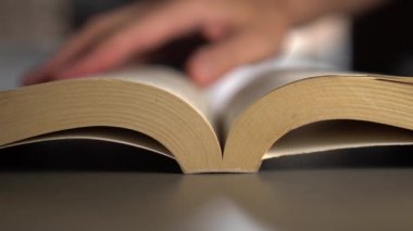Adam eski bir kitap gri bir yüzey üzerinde sayfaları dönüm ile yapraklar. Kütüphanede. yavaş çekim