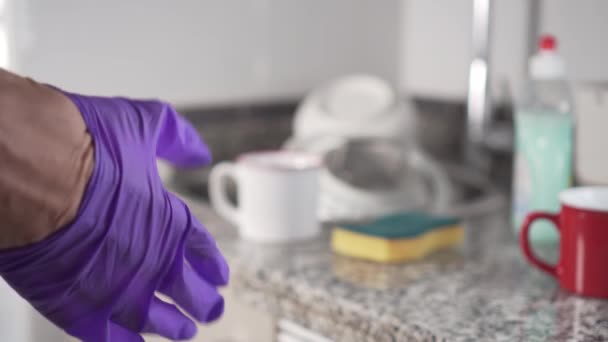 年轻人在衣服拉右蓝色防护手套洗碗在厨房水槽 — 图库视频影像