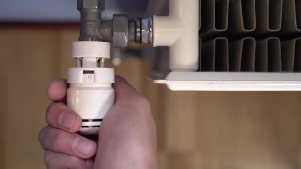 A man s hand turns a thermostat on a white heating radiator to add room temperature. Blue walls and brown parquet — Stock Footage Man Hand Turns Thermostat White Heating Radiator Add Room Temperature Royalty Free Stock Footage