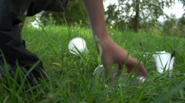 genç adam gri bir çanta içinde çim üzerinde plastik çöp toplar. Plastik çöp ile gezegenin doğasının kirlilik sorunu