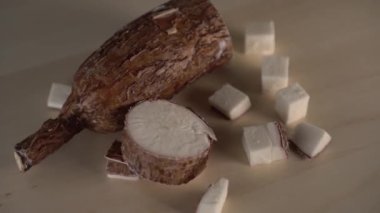 Ahşap bir mutfak tahtası üzerinde yucca kökü dilimlenmiş parçalar. Egzotik yemeklerşifa