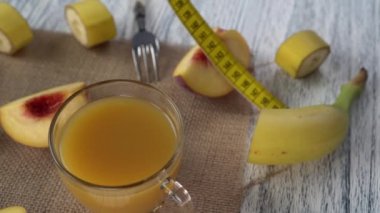 Şeftali, cam bardak bardak suyu ve çuval bezi üzerinde bir çatal ve bir santimetre ile ahşap bir masa