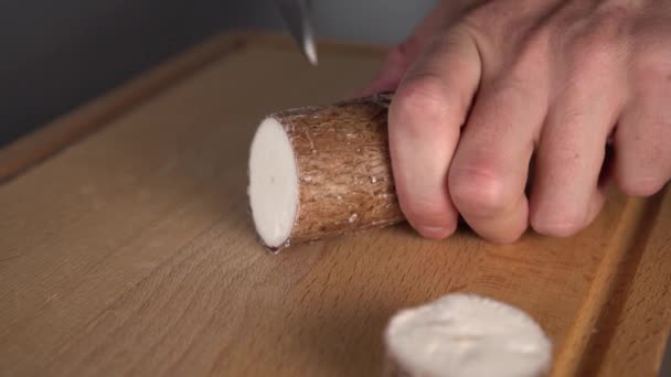 一只手用刀在灰色的桌子上的木制厨房板上割下玉卡根 在家烹饪健康菜肴 — 图库视频影像