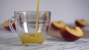 Şeftali suyu dilimlenmiş şeftali ile ahşap bir masa üzerinde bir cam kupa içine dökülür