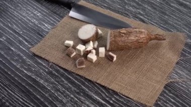 Bir çuval bezi ve siyah ahşap masa üzerinde yucca kökü Dilimleri