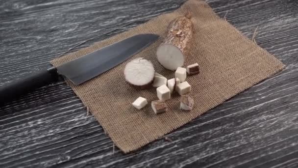 Plakjes Yucca wortel op een zak en zwarte houten tafel — Stockvideo