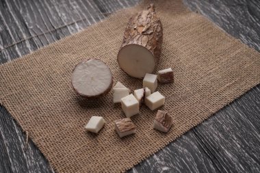 Siyah ahşap bir masa üzerinde bir çuval bezi üzerinde dilimlenmiş yucca kökü