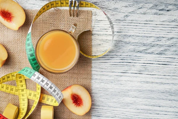 Een glas perzik SAP op een doek op een witte houten tafel met plakjes fruit en een vork en een centimeter — Stockfoto