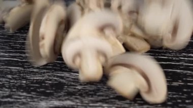 Doğranmış champignon mantar bir yığın siyah ahşap bir masa üzerine düşer. Vejetaryen yemek pişirme