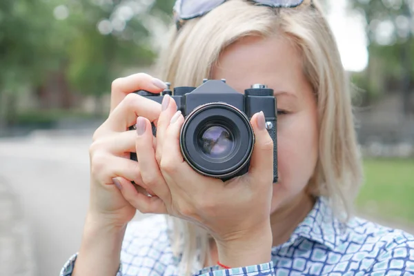 Sarışın kız bir kamera tutar ve ormanda odaklanır — Stok fotoğraf