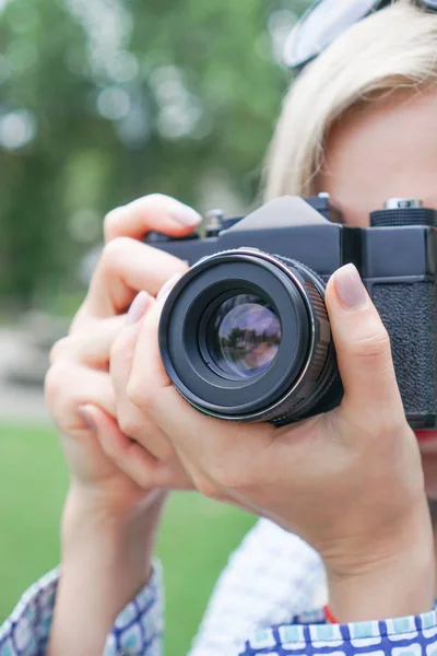 Menina loira com uma câmera se concentra no parque — Fotografia de Stock