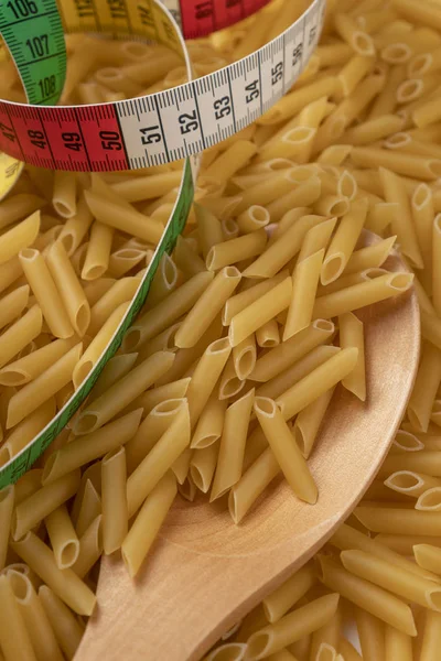 Centímetro multicolor y una cucharada de madera en un montón de pasta de trigo —  Fotos de Stock