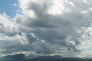 Arka ışıkta berrak mavi gökyüzüne karşı dağların tepesinde gök gürültüsü