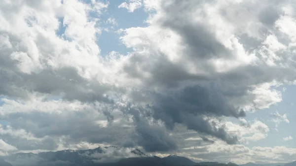 バックライトの澄んだ青空に対して山の頂上に雷雲 — ストック写真