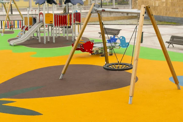 Empty playground with swings and safe rides with anti-traumatic bright rubber crumb coating
