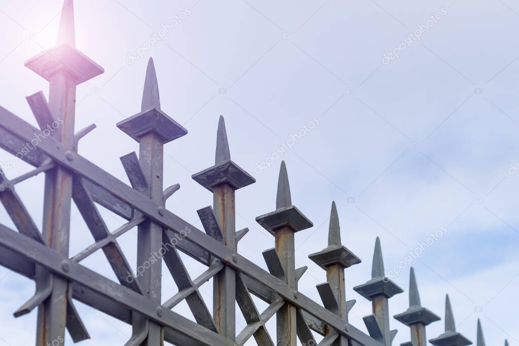 Metal patterned fence with peaks against a clear blue sky