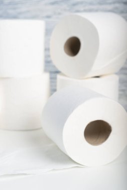Mavi duvar dokusunun arka planında beyaz bir masanın üzerinde bir yığın tuvalet kağıdı yuvarlanıyor. Doğal maddeleri hijyen ürünleri için kullanma kavramı