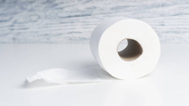 Tuvalet kağıdı beyaz bir masanın üzerinde ahşap bir mavi duvarın arka planında yuvarlanıyor. Biyolojik malzemeleri hijyen için kullanma kavramı