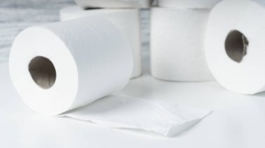 Mavi duvar dokusunun arka planında beyaz bir masanın üzerinde bir yığın tuvalet kağıdı yuvarlanıyor. Hijyen ürünleri