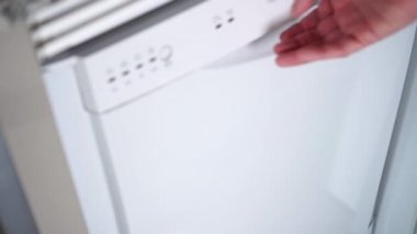 Bir adam bulaşık makinesinin kapısını açar, orada yıkanmış ve temiz bulaşıklar vardır. Tabaklar, kupalar, kaşıklar, çatallar.