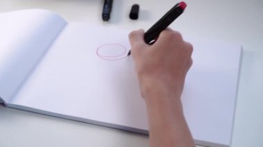 Bir gencin eli, beyaz boş bir albüm kağıdına keçeli kalemle resim çizer. Eğitimde yaratıcı görevler kavramı