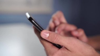 Bir genç odadaki beyaz bir masada dokunmatik ekranlı cep telefonu kullanıyor. Tuş takımı için el hareketleri. Gençler ve gençler arasında popülerlik kavramı ve sosyal ağların tehlikesi