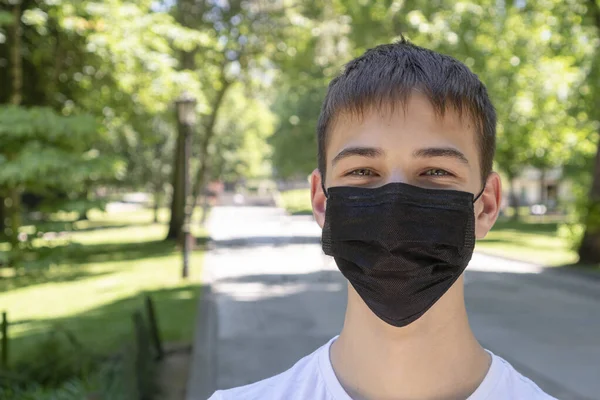 Joven Ríe Con Una Máscara Negra Médica Parque Vacío Sobre — Foto de Stock