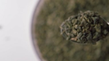 Yeşil çay barutu. Metal kaşıkta kurumuş yapraklar. Makro atış. Seçici odaklanma. Çin geleneksel aromalı içecek.