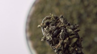 Yeşil çay barutu. Metal kaşıkta kurumuş yapraklar. Düşüş. Ağır çekim. Makro atış. Seçici odaklanma. Çin geleneksel aromalı içecek.