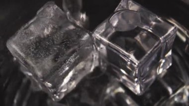 Mineral karbonat suyu, bir sürü köpüklü baloncuğun yakın çekim oluşturduğu bir bardakta buz küplerine dökülür. Makro çekim