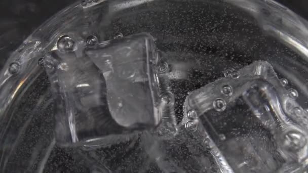 Draai Bubbels Een Glas Gecarboniseerd Transparant Water Met Bewegende Ijsblokjes — Stockvideo