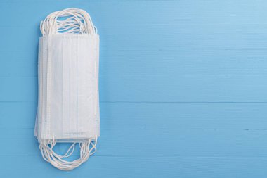 Açık mavi ahşap bir arka planda tıbbi koruyucu maske yığını. Kopyalama alanı