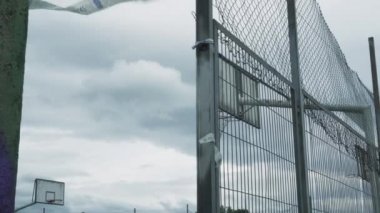 Oviedo - İspanya, 13 Haziran 2020: Koronavirüs 'ün basketbol potalarıyla karantinaya alınmasının ardından spor sahasının kilitleri açıldı. Demir tel örgülerin arkasında. Yasaklama bandı rüzgarda dalgalanıyor