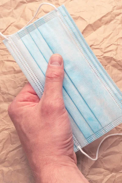 Máscara Azul Protectora Médica Una Mano Sobre Fondo Papel Marrón — Foto de Stock