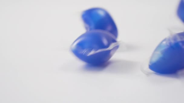 白い背景に落ちる青い食器洗い機ジェルポッドのクローズアップ ホームクリーニング製品 スローモーション — ストック動画